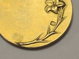 a gold medal with a flower on it on a table
