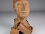 une sculpture en argile représentant une tête d'homme d'où dépasse un morceau de bois