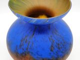 a blue vase with a yellow center sitting on a white surface