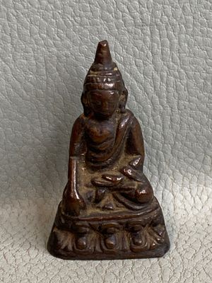 figurine de Bouddha assise sur une surface en cuir blanc, sur fond blanc