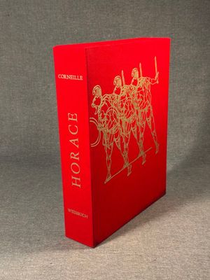 a red book with gold foil on it sitting on a table