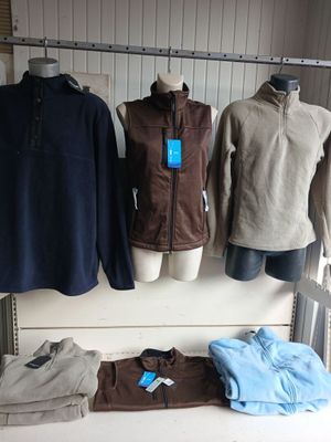 plusieurs vestes et pulls suspendus à un portant dans un magasin de vêtements