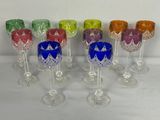 Plusieurs verres à vin de différentes couleurs sont alignés sur une table