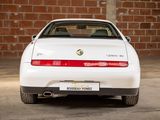 a white sports car parked in front of a brick wall