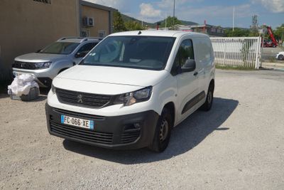 une camionnette blanche garée dans un parking à côté d'autres voitures
