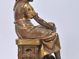 bronze statue of a woman sitting on a stool with a dog