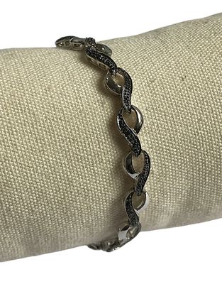 bracelet en argent orné de diamants noirs, posé sur un tissu blanc