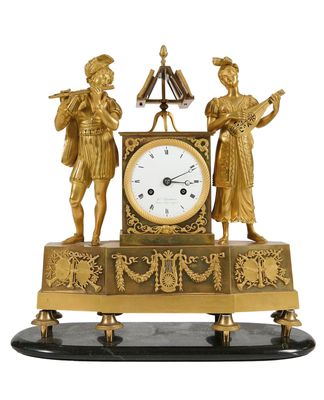 une horloge en or surmontée de deux figurines