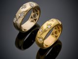 two gold rings with diamonds on a black surface
