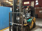 un chariot élévateur dans un entrepôt, avec un mur bleu en arrière-plan