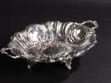 an antique silver plate on a black surface with a black background