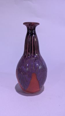 un vase violet posé sur une surface blanche