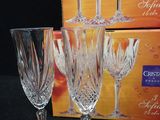four crystal wine glasses sitting on top of a table next to a box of wine glasses
