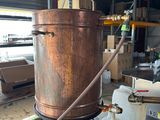 a large copper pot sitting on top of a wooden table