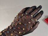 someone is holding a pair of gloves with multi colored stones on them