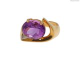 gros plan d'une bague en or avec une pierre violette