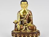 a bronze statue of a person sitting on a table