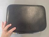 a person holding a black purse on a white surface