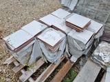 une pile de cartons posée sur une palette, à côté d'un tas de pierres