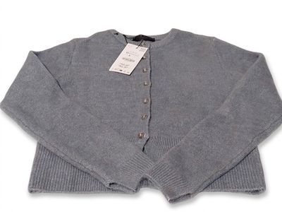 Le pull est gris et comporte des boutons sur le devant.