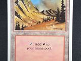 a close up of a card on a table with a mountain in the background