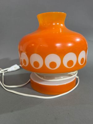 un vase orange orné de cercles blancs, posé sur une table