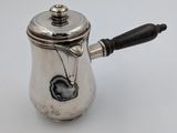 une cafetière en argent avec une poignée noire sur un fond blanc