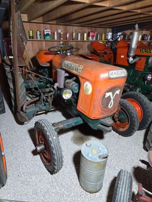 a small tractor in a garage with other farm equipment