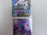 two pokemon cards in plastic packaging on a white surface