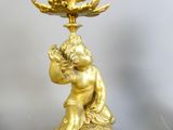 une statue en or représentant un enfant, surmontée d'une fleur