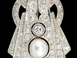un gros plan sur une broche en perle blanche et diamants