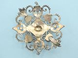 an image of a brooch made of silver metal on a blue surface