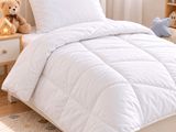 a bed with a white comforter and a teddy bear