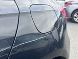 a black car parked in a parking lot with other cars in the background