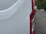 a white van parked in a parking lot with trees in the background