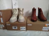 trois paires de bottes sont posées sur des cartons, sur un lit