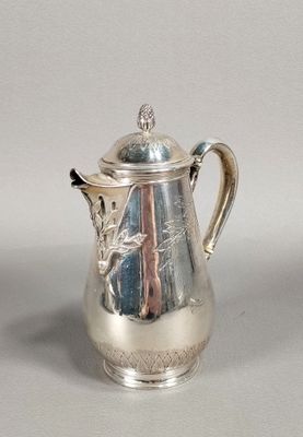 a silver coffee pot with a lid on a table