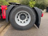a red semi truck with a flat tire parked in a parking lot