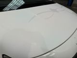 a car that has been painted white and has a tie on the hood of it