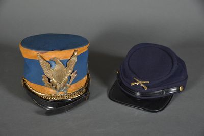 pair of military hats with eagle emblem on them on a gray surface