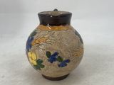 a small vase with flowers painted on it on a white surface