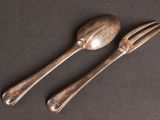 two spoons and a fork on a table with a black background