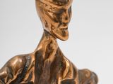 bronze statue of a man sitting on a bench with a hat on his head