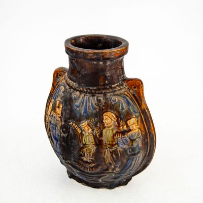 un vase marron orné d'une peinture, posé sur une surface blanche