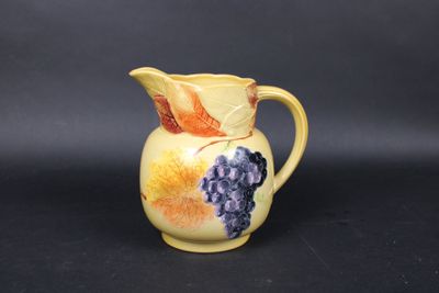 an image of a yellow pitcher with grapes painted on it