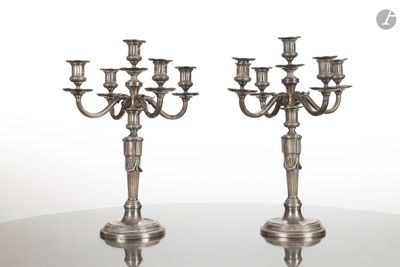 paire de chandeliers anciens en métal argenté posés sur une table en verre