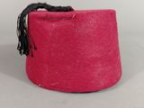 pink felt hat with black tassel on a white background