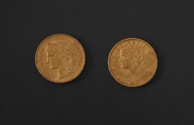 two gold coins on a black surface with a black background