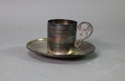 a silver cup and saucer sitting on a saucer
