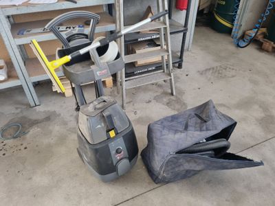 un aspirateur posé par terre à côté d'un sac